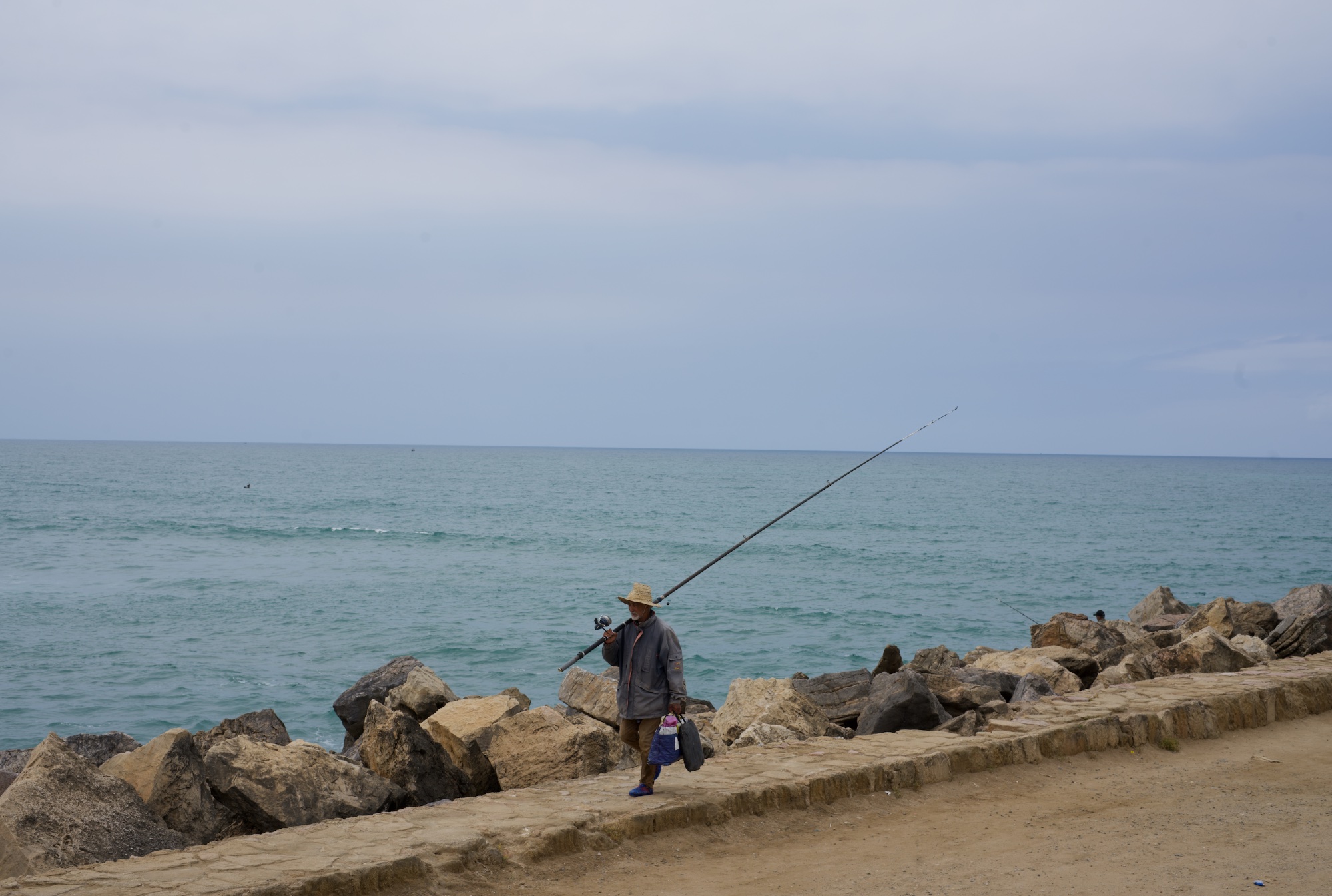 Fisherman on rocky shoreline